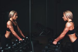 Home Fitness Trainer A Opleiding: professionele fitnesstrainer demonstreert correcte trainingstechniek met halter in sportschool